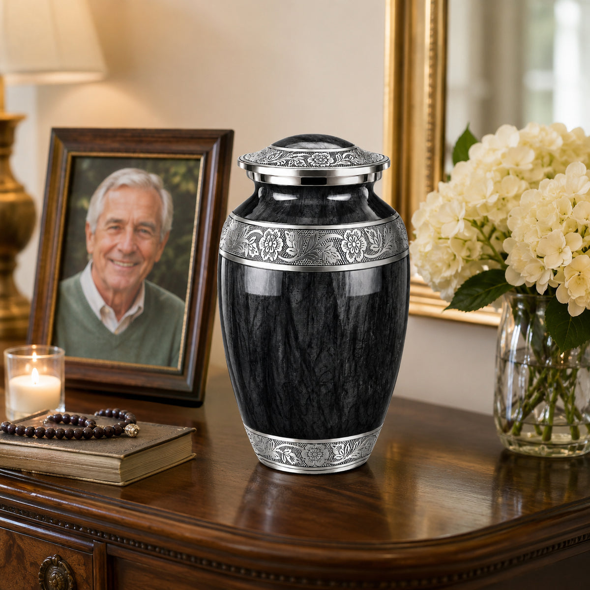 Black memorial urn on marble surface in church with stained glass windows, white roses, and framed portrait