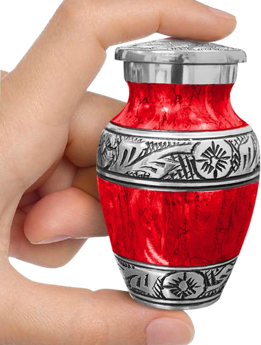 Red watercolor keepsake cremation urn held between fingers showing size